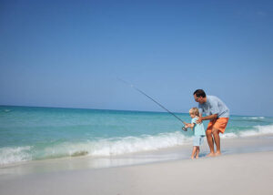 Father and his little boy fishing on the shore of a Ocracoke beach.